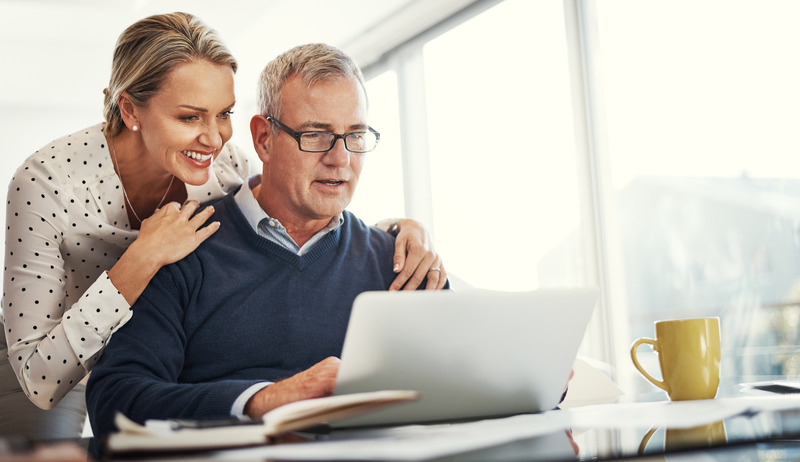 Shot of a mature couple using a laptop while going through paperwork at home